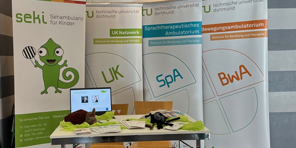 Foto eines Infostandes, Tisch mit Infomaterial und vier Aufsteller im Hintergrund von seki, UK, SpA und BwA